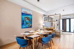 Ein moderner Essbereich mit einem Holztisch, gedeckten Plätzen für vier Personen, blauen Sitzmöbeln und einem großen Gemälde einer Meeresschildkröte an der Wand.