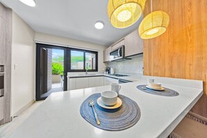 A modern kitchen with a central island, a built-in oven, and a view of the outdoors. - LUX 3BR House Pool Gym 7-Min Walk Palm Beach - Porta Al Sole 6 by Bocobay (Noord)