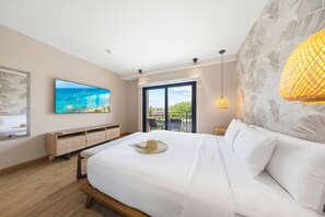 Ein modernes Schlafzimmer mit einem großen Bett, einem Flachbildfernseher, einem Balkon mit Sitzgelegenheit und einem großen Fenster.