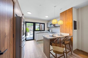A modern kitchen with a central island, wooden cabinets, and a view to an outdoor patio.