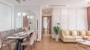 A modern living room with a sofa, a dining table with chairs, and a large mirror. - Vinhomes Skylake Lynn Housing (Hanoi)