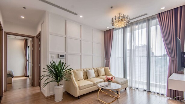 A modern living room with a beige sofa, a round coffee table, and a potted plant. - Vinhomes Skylake Lynn Housing (Hanoi)