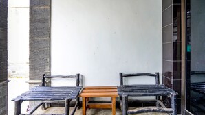 A small outdoor seating area with a wooden table and two chairs. - SPOT ON 92480 Iwn Homestay Syariah (Banyuwangi)