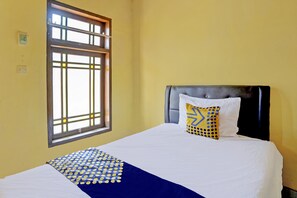 A neatly made bed with a blue and white polka dot bedspread and a single pillow with a geometric pattern. - SPOT ON 92480 Iwn Homestay Syariah (Banyuwangi)