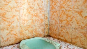 A bathroom with a green squat toilet, tiled walls, and a tiled floor. - SPOT ON 92480 Iwn Homestay Syariah (Banyuwangi)