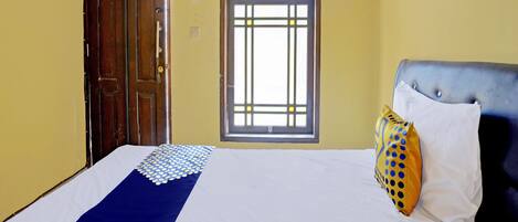 A hotel room with a bed, a window, and a door.