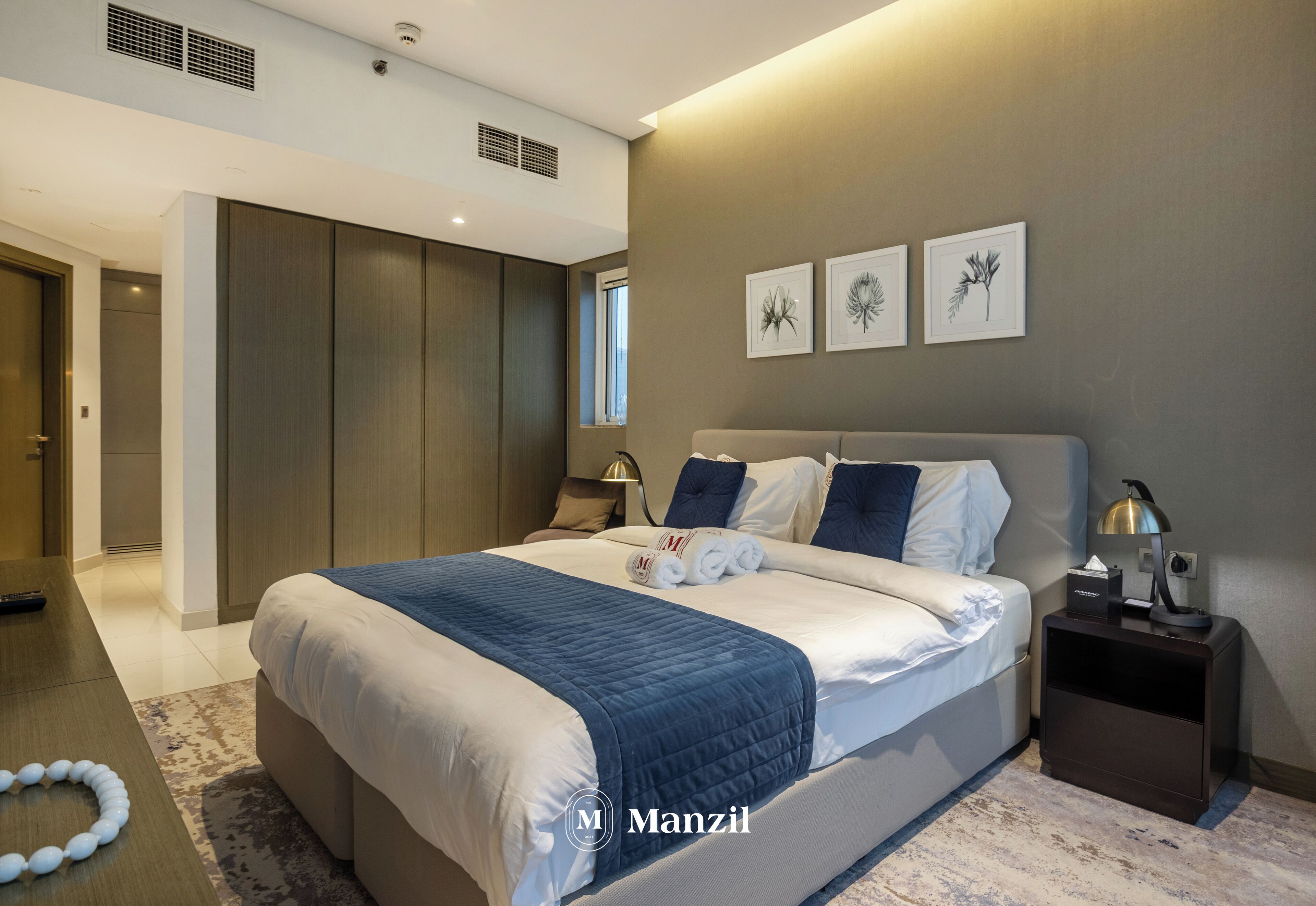 A modern bedroom with a large bed, bedside tables, and artwork on the wall.