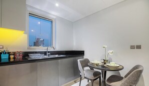 Eine moderne Küche mit schwarzem Arbeitsplatz, einem Fenster und einem Essbereich mit zwei Stühlen und einem Tisch.