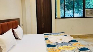 Una cama bien hecha con una colcha estampada, un cabecero de madera y una ventana con vistas a la vegetación.