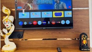 Un televisor de pantalla plana montado en una pared de madera con un estante debajo.