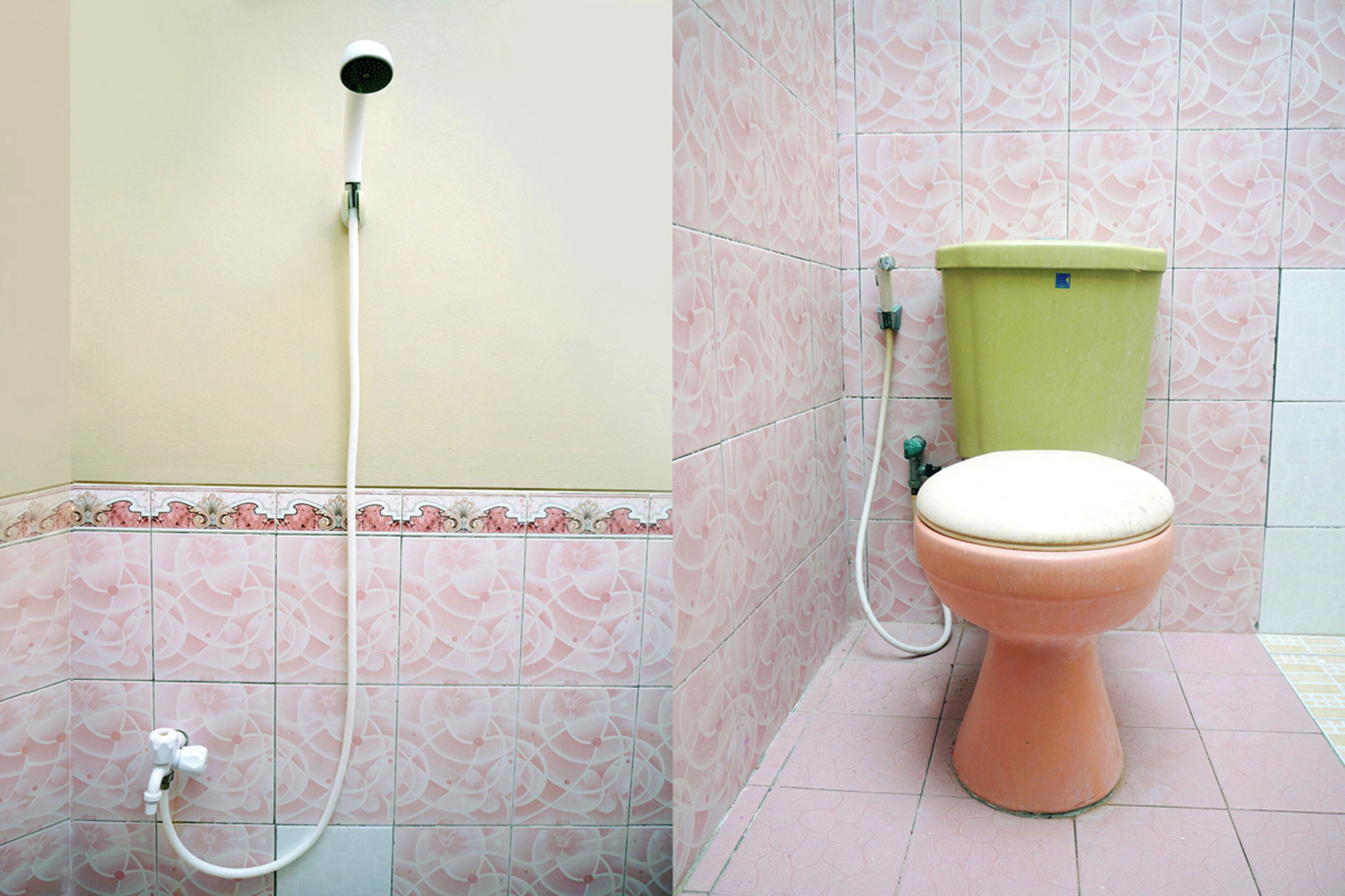 A bathroom with a toilet, a shower head, and pink patterned tiles.