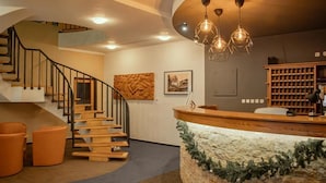 A modern reception area with a wooden staircase, a reception desk, and a bookshelf. - Hotel Esprit (Špindlerův Mlýn)