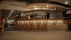 A bar area with a curved counter, multiple stools, and a stone wall backdrop. - Hotel Esprit (Špindlerův Mlýn)