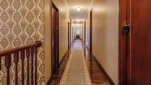 A long, narrow hallway with wooden doors and a patterned carpet. - Royal Hotel Dungog (Dungog)