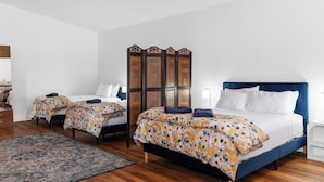 A bedroom with a large bed, two smaller beds, a wooden partition, and a patterned rug. - Royal Hotel Dungog (Dungog)