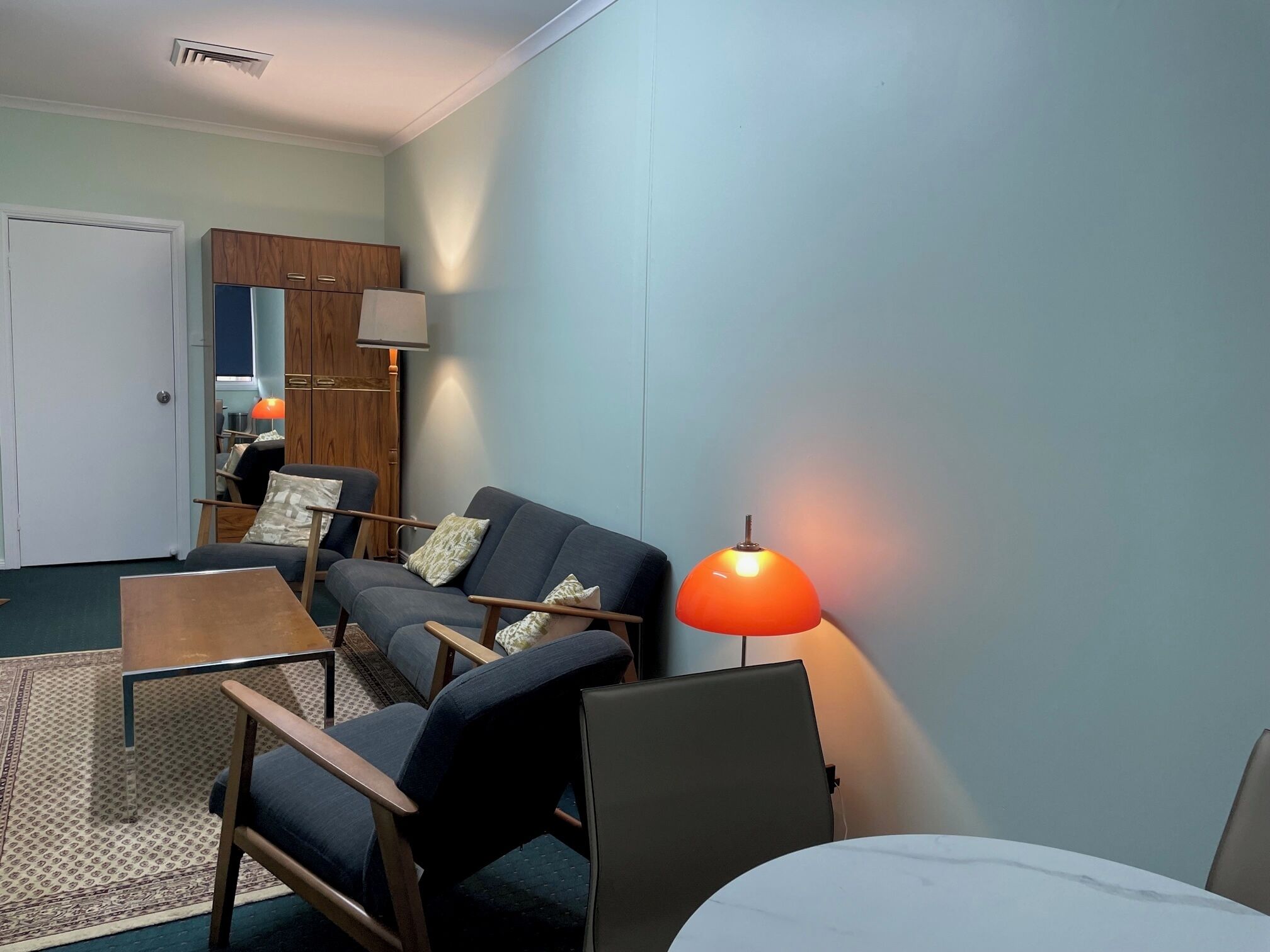 Una sala moderna con sofá, sillones, una mesa de centro y una lámpara.