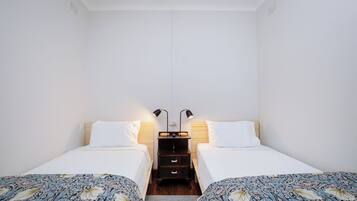 Habitación doble con dos camas, una mesita de noche con lámparas y suelo de madera.