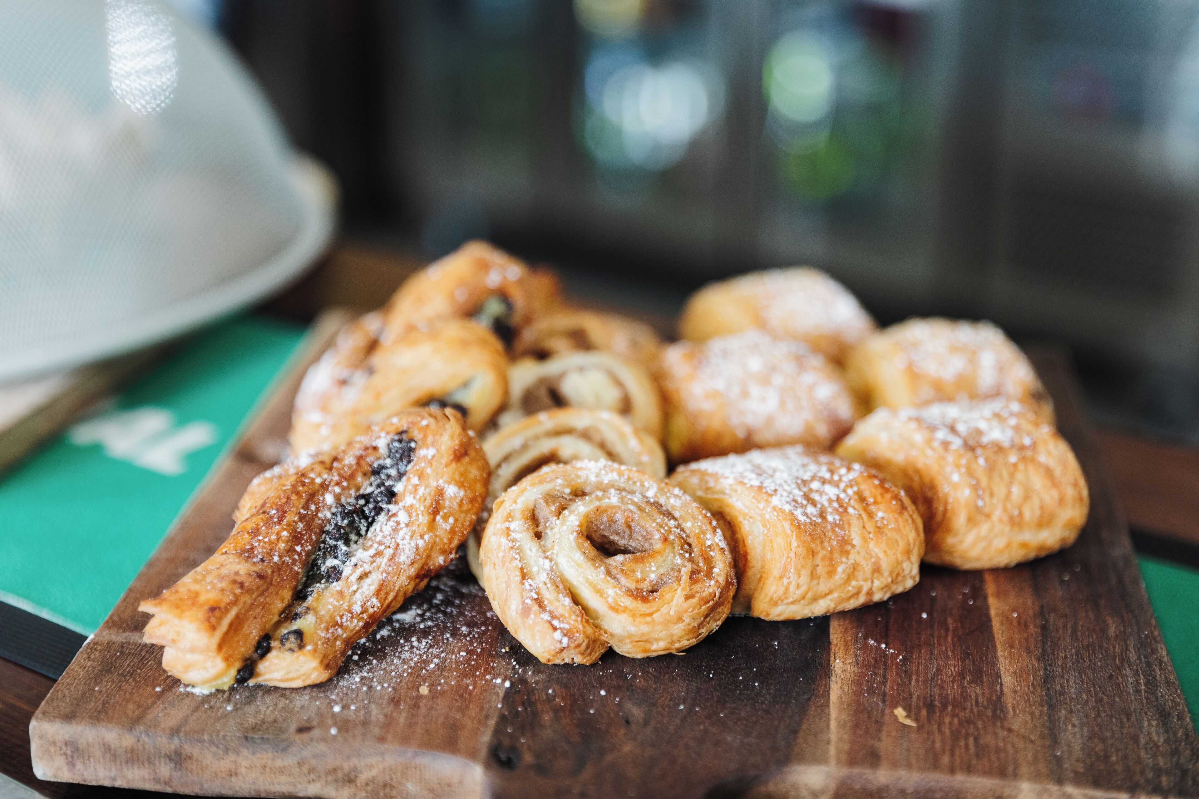 A wooden board with various pastries, including a rolled pastry and a chocolate-filled pastry.
