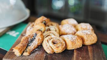 A wooden board with various pastries, including a rolled pastry and a chocolate-filled pastry.