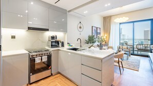 A modern kitchen with a built-in oven, microwave, and sink. There is a dining area with a view of the city. - Canal and Burj Khalifa Views, Mins Drive to Downtown Dubai (Dubai)