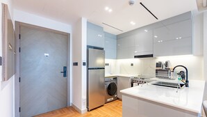 A modern kitchen with a built-in washing machine, a refrigerator, and a coffee maker. - Canal and Burj Khalifa Views, Mins Drive to Downtown Dubai (Dubai)