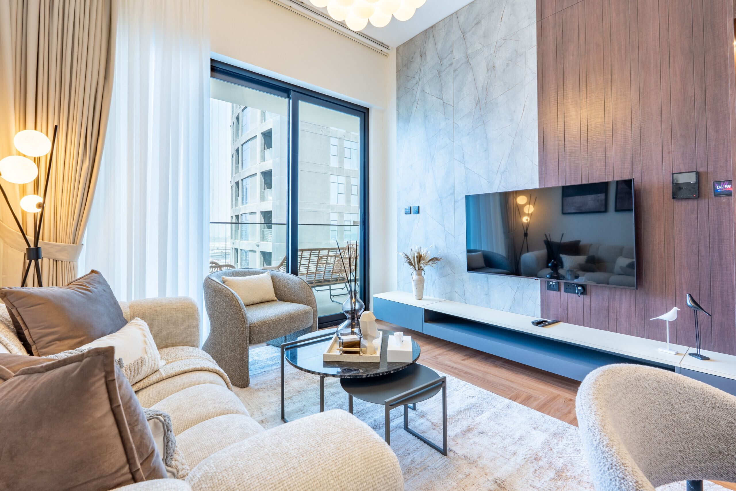 Un salon moderne doté d’un grand téléviseur, de sièges confortables et offrant une vue sur la ville.
