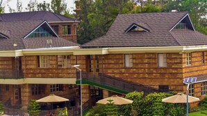 A building with a brick facade, multiple windows, and a covered outdoor area with tables and chairs. - Dancourt Funfair Thika (Thika)