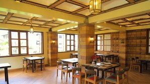 A restaurant with wooden tables and chairs, large windows, and a brick wall. - Dancourt Funfair Thika (Thika)