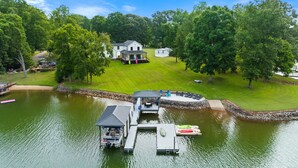 Une propriété au bord du lac, dotée d’un quai, d’un bateau et d’une maison entourée d’une végétation luxuriante.