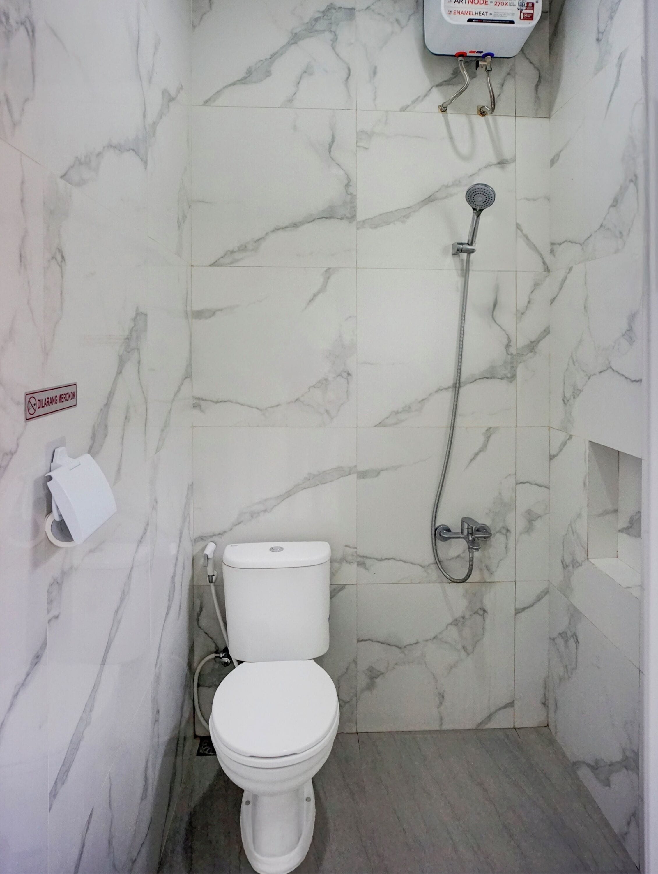 Un baño con inodoro, ducha y dispensador de papel higiénico en la pared.