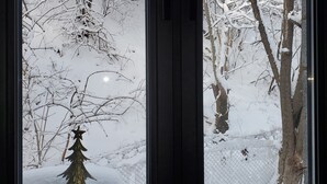 A window with a view of a snow-covered landscape and a small Christmas tree decoration.