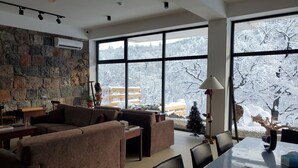 A spacious living room with a stone wall, large windows, and a view of a snowy landscape.