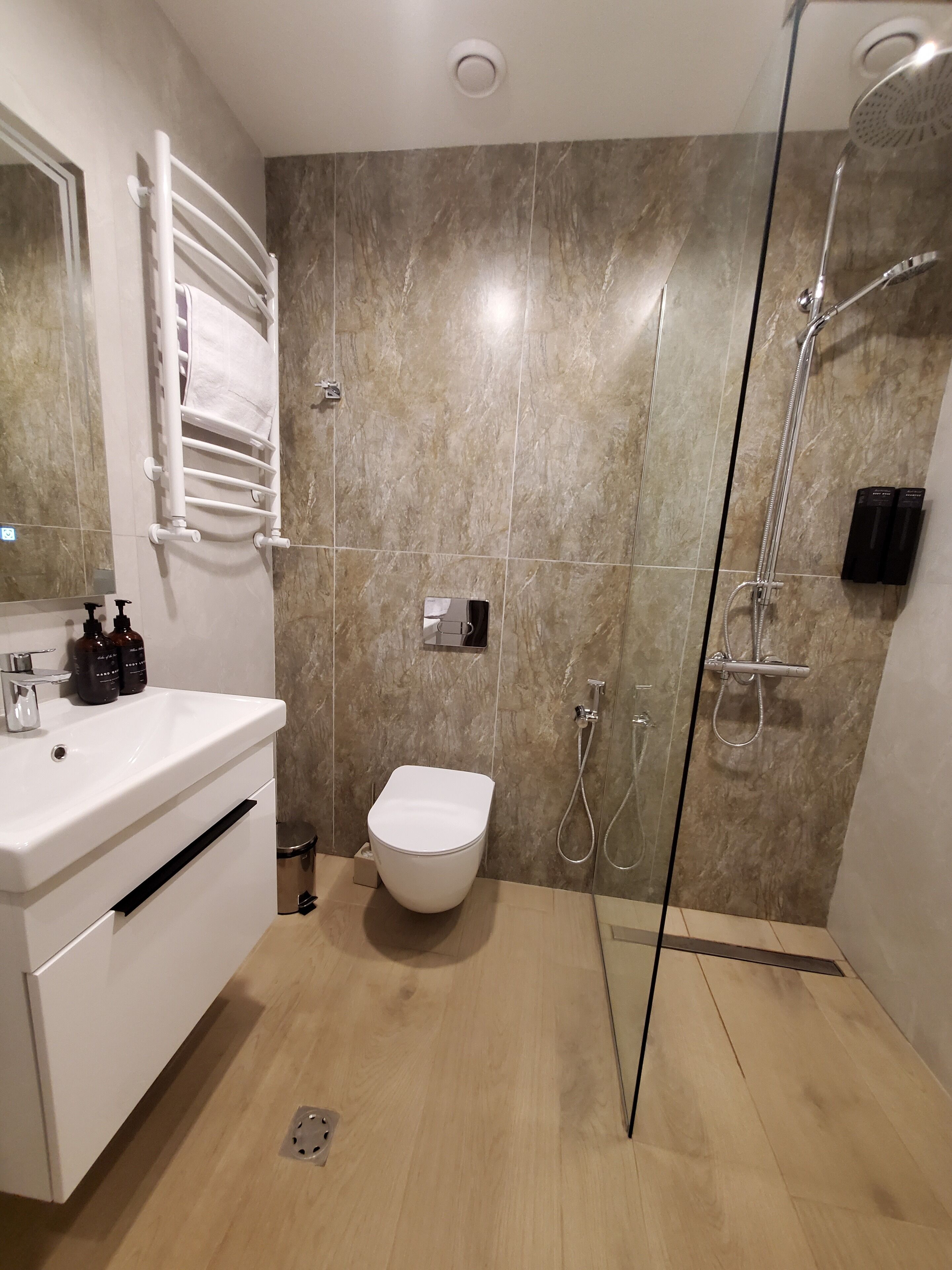 A modern bathroom with a white sink, a toilet, and a glass-enclosed shower area.