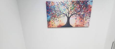 A conference room with a black table, four black chairs, and a colorful tree painting on the wall.