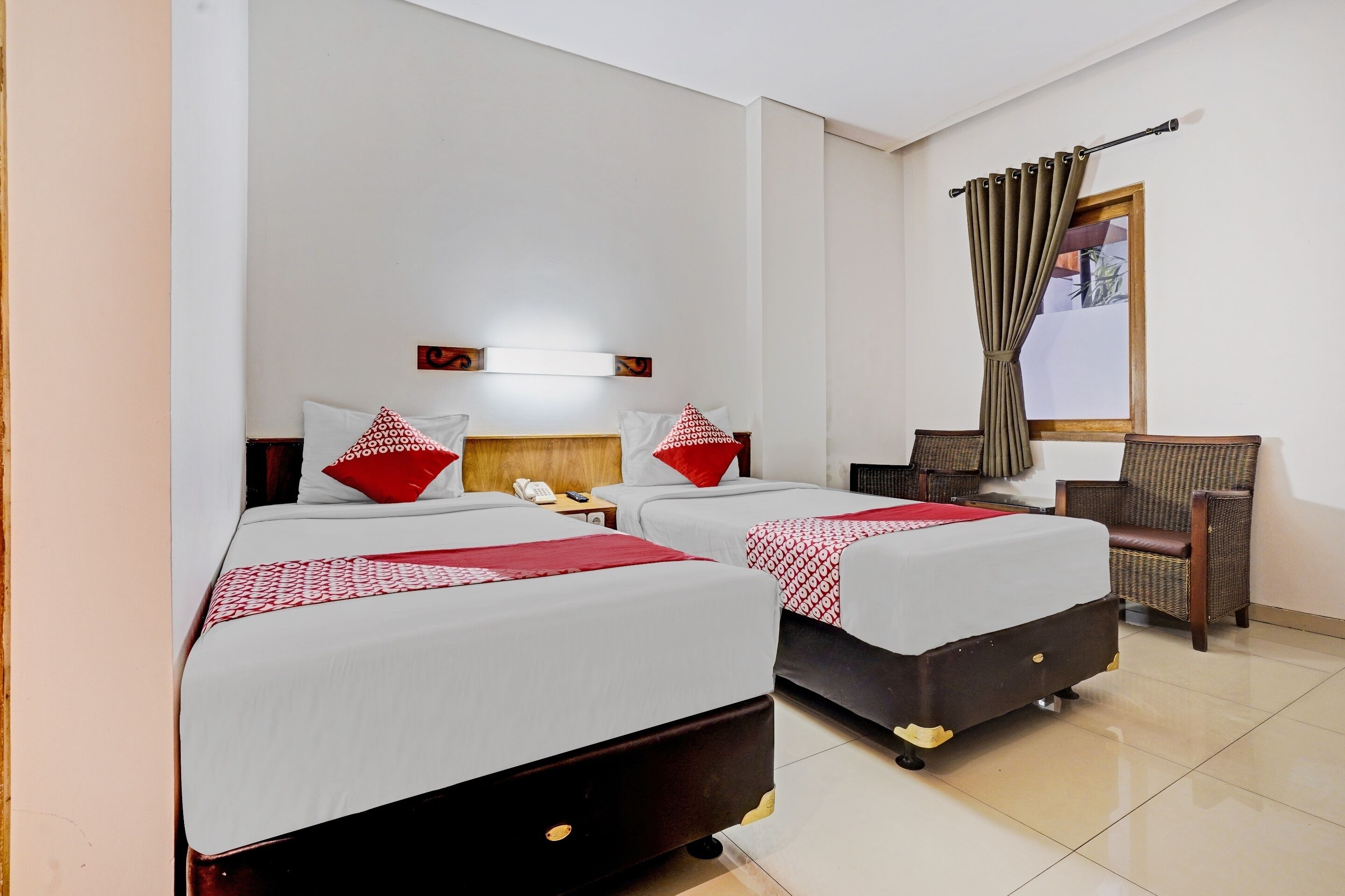 A hotel room with two beds, a chair, a desk, and a mirror.