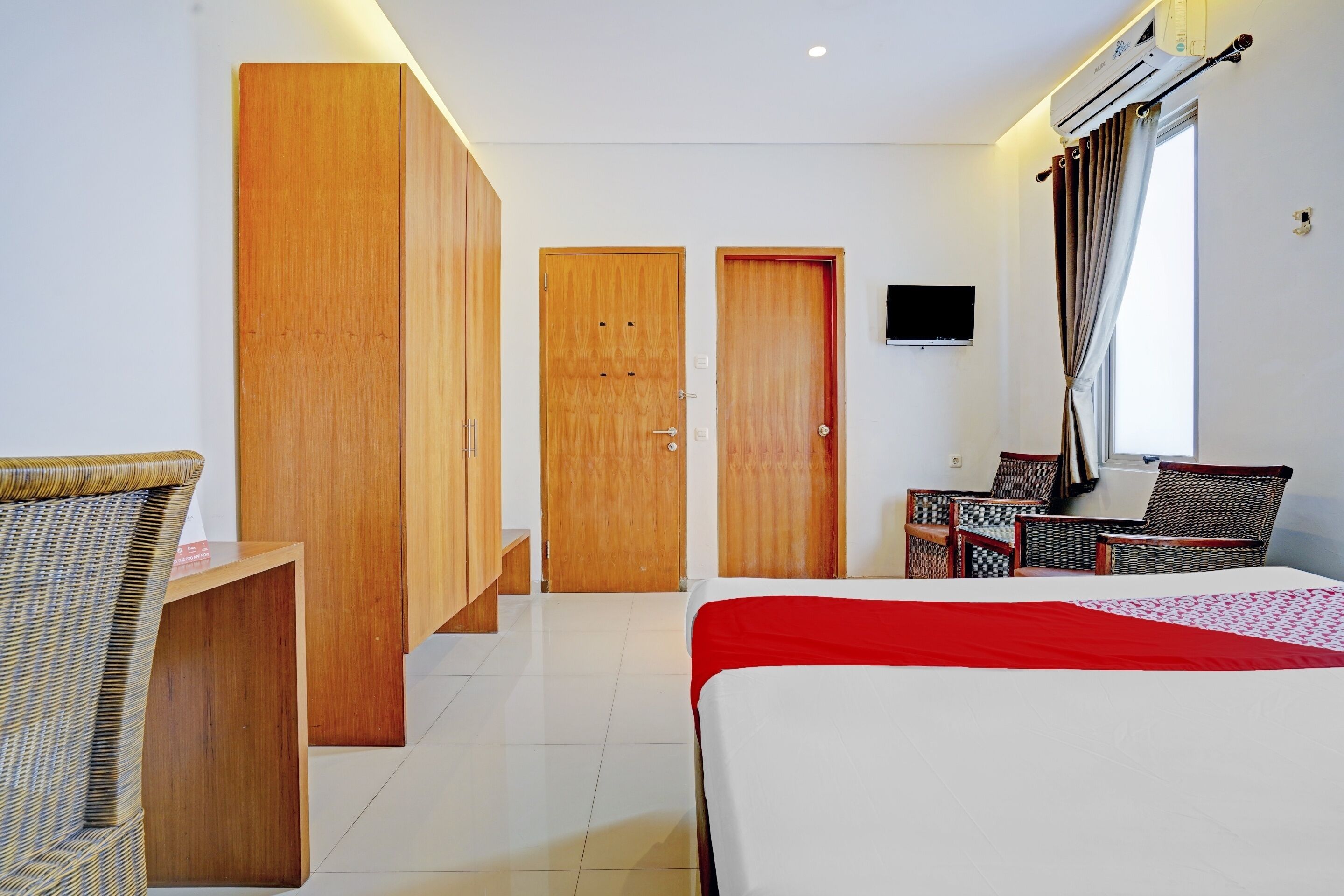Una habitación de hotel con cama, escritorio, silla, televisor y armario.