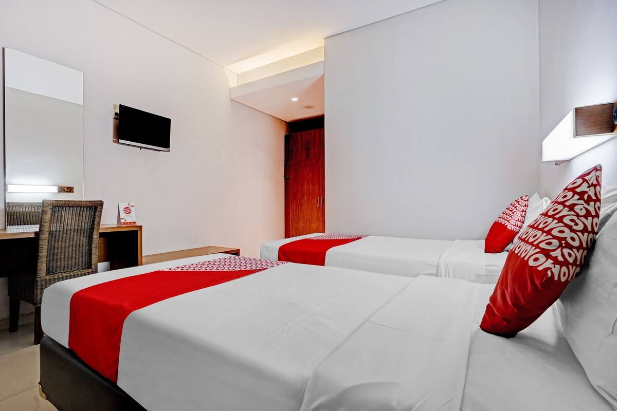 Habitación de hotel con dos camas, un escritorio, una silla, un televisor y un armario.