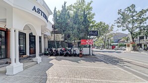 A hotel named ASTERIA with a paved sidewalk, parked motorcycles, and a signboard for the hotel.