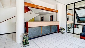 A reception area with a wooden reception desk, a clock, and a staircase leading to upper floors.