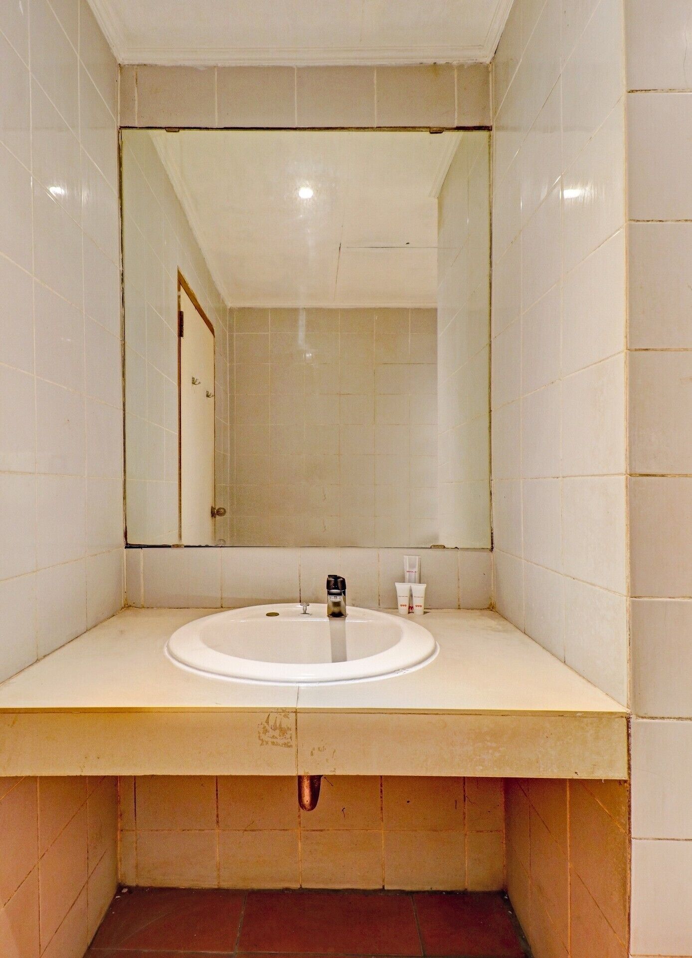 A bathroom with a white sink, a mirror, and a towel dispenser.
