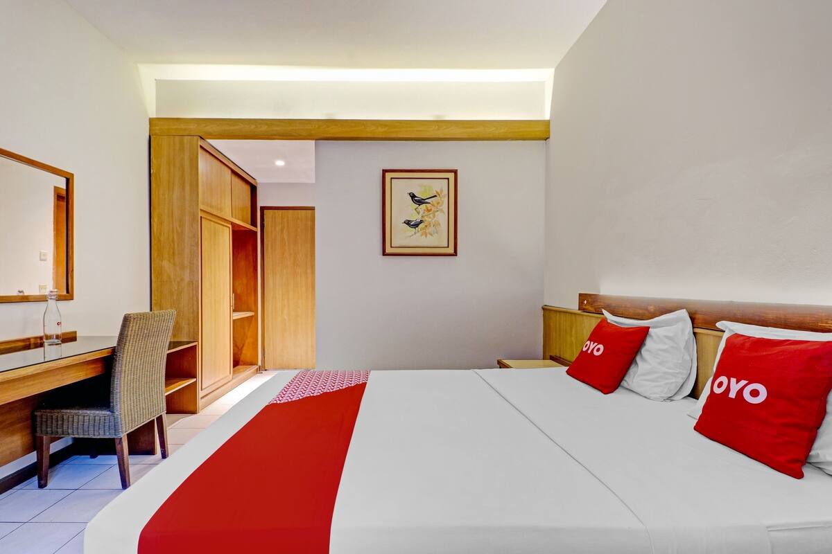 Une chambre d’hôtel avec un lit, un bureau, une chaise et une armoire.
