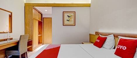Ein Hotelzimmer mit Bett, Schreibtisch, Stuhl und Kleiderschrank.