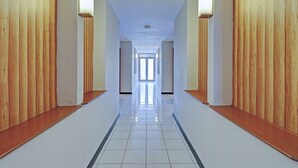 A long, narrow hallway with wooden paneling on the walls and a shiny tiled floor. - OYO 94726 Asteria Talaga Bodas (Bandung)