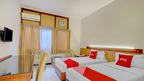 A hotel room with two beds, a desk, a chair, and a television.