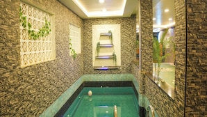 A swimming pool with a stone wall and a white lattice window. - Le Avirah (Vanur)