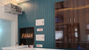 A modern kitchen with a marble countertop, teal wall paneling, and a built-in stove. - Le Avirah (Vanur)