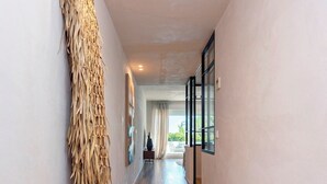 A hallway with wooden flooring, a large woven wall hanging, and a white vase. - Exclusive Loft With Private Terrace in Marbella. Incosol II (Marbella)