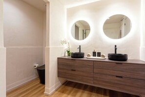 A modern bathroom with a wooden vanity, two round mirrors, and a black sink. - Exclusive Loft With Private Terrace in Marbella. Incosol II (Marbella)