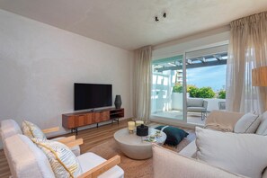A modern living room with a flat-screen TV, a round coffee table, and a sofa. - Exclusive Loft With Private Terrace in Marbella. Incosol II (Marbella)