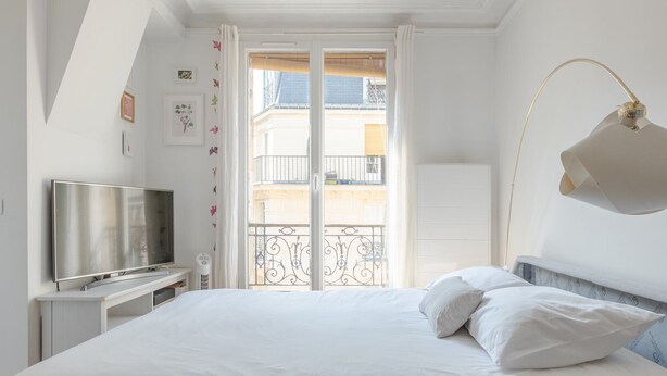 A bedroom with a bed, a TV, and a balcony with a railing. - Authentic Paris Living – Steps from Montmartre (Paris)